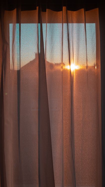 Luz cálida de amanecer entrando por una cortina