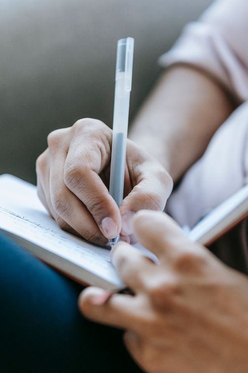 Una mano escribiendo en un cuaderno con luz cálida